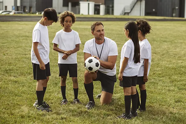 Kids playing football supervised by football trainer